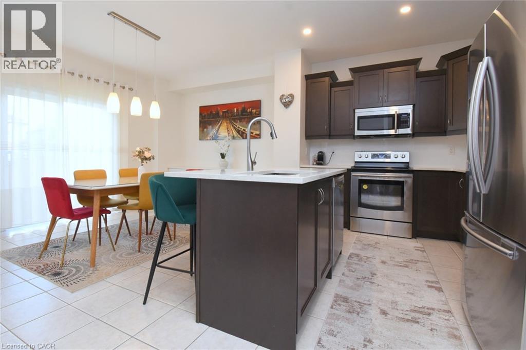 Kitchen featuring an island with a white countertop and dark cabinetry, stainless steel appliances, and recessed lighting - 25 Guest Street, Hamilton, ON