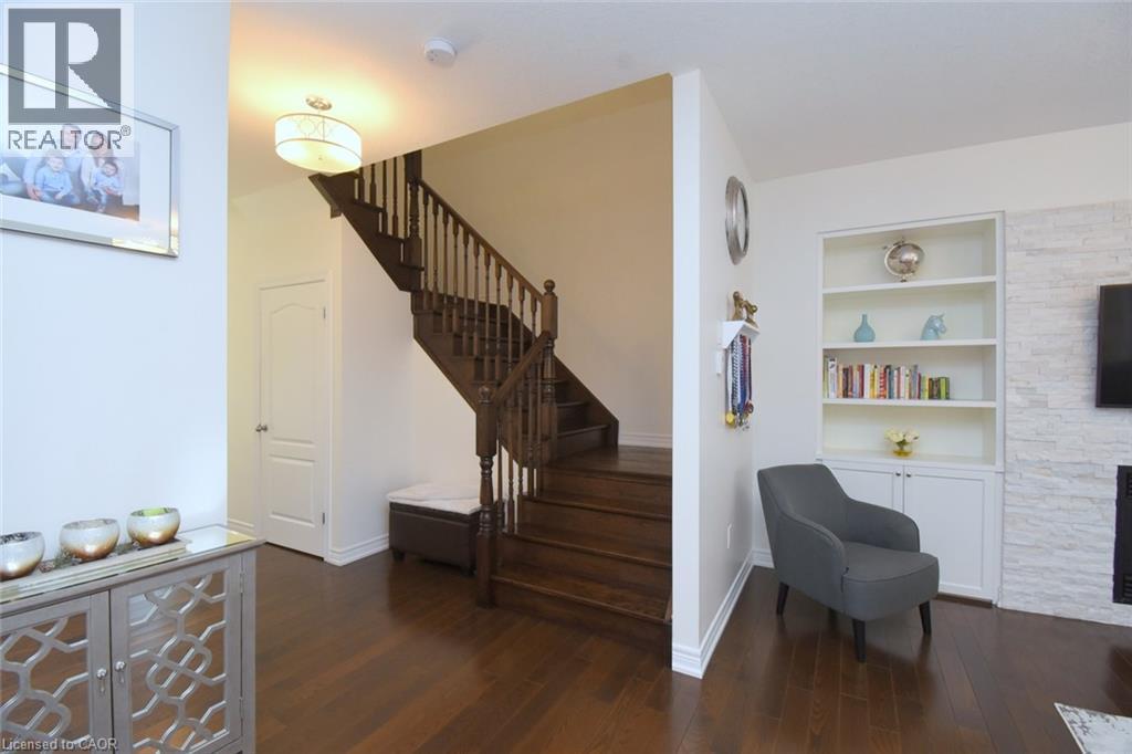 Wood-finish flooring throughout, featuring a dark wood staircase with spindle railings - 25 Guest Street, Hamilton, ON
