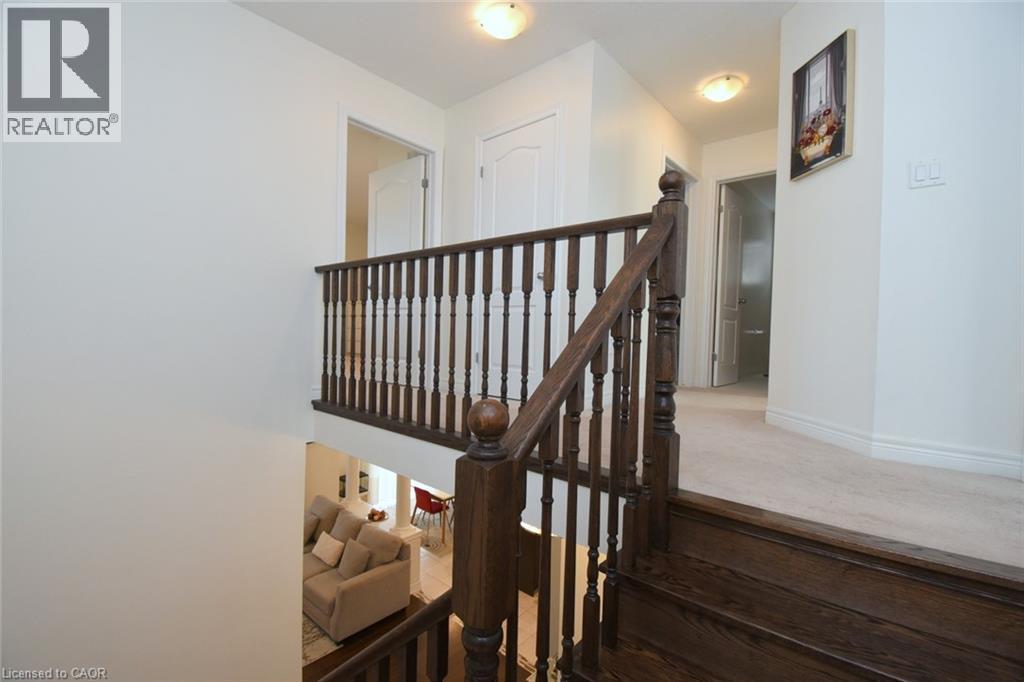 Wood-finish staircase with dark banister, light-colored wall paint, and recessed ceiling lighting - 25 Guest Street, Hamilton, ON