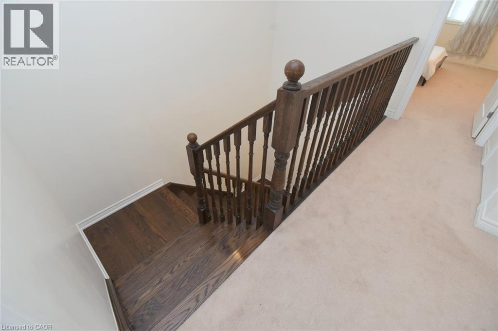 Staircase featuring wood-finish treads and risers, a wood-finish newel post, and wood-finish balusters - 25 Guest Street, Hamilton, ON