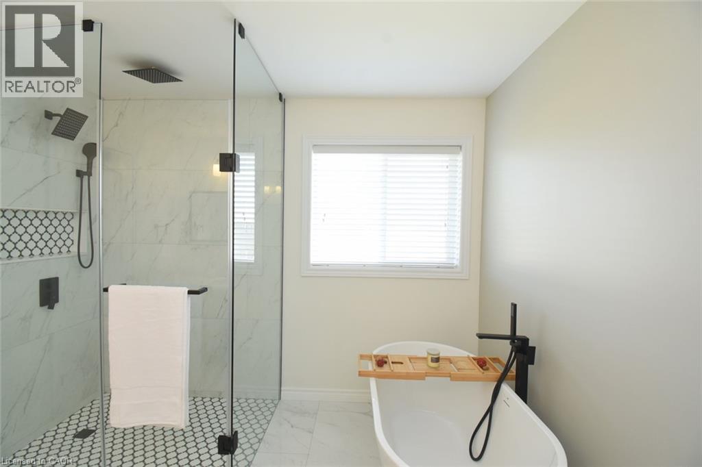 Freestanding soaking tub with a floor-mounted matte black faucet - 25 Guest Street, Hamilton, ON