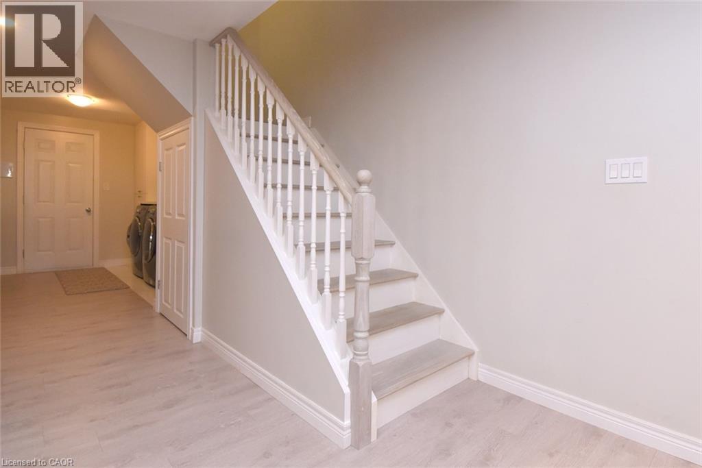 Staircase with painted risers and wood-finish treads, light-toned wood-finish flooring, and a paneled interior door - 25 Guest Street, Hamilton, ON