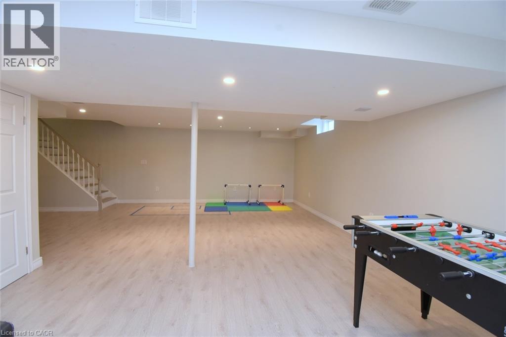 Expansive finished lower level featuring recessed lighting, wood-finish flooring, and a white painted staircase - 25 Guest Street, Hamilton, ON