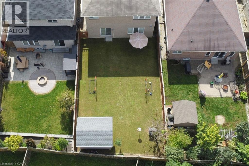 Expansive backyard with a manicured lawn, a built-in outdoor storage shed, and a privacy fence - 25 Guest Street, Hamilton, ON