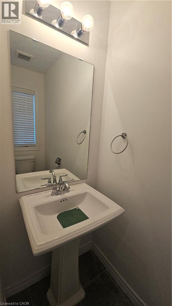 Pedestal sink with chrome faucet, large wall-mounted mirror, and vanity lighting - 3 Sharp Drive, Ancaster, ON