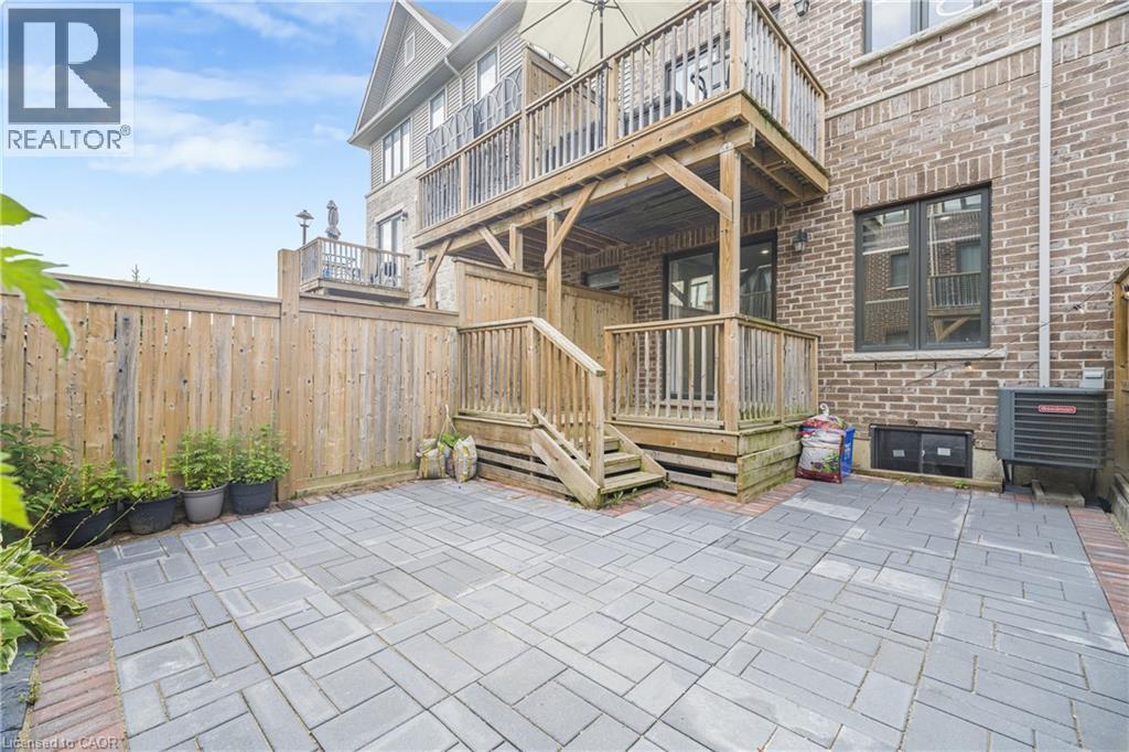 Paved patio area, wooden privacy fencing, multistory wooden deck, brick exterior, and multiple large windows - 1890 Rymal Road E Unit# 144, Hamilton, ON