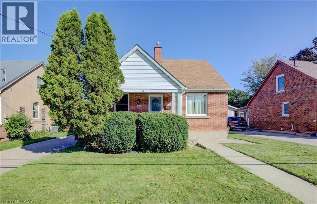 Brick exterior featuring white siding gables, an asphalt shingle roof, and a concrete walkway - 174 Bridgeport Road E, Waterloo, ON