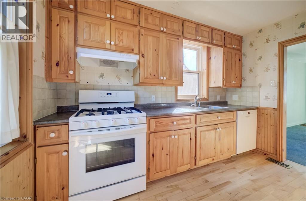 Kitchen featuring wood-finish cabinetry, a gas range, stainless steel sink, and wood-finish flooring - 174 Bridgeport Road E, Waterloo, ON