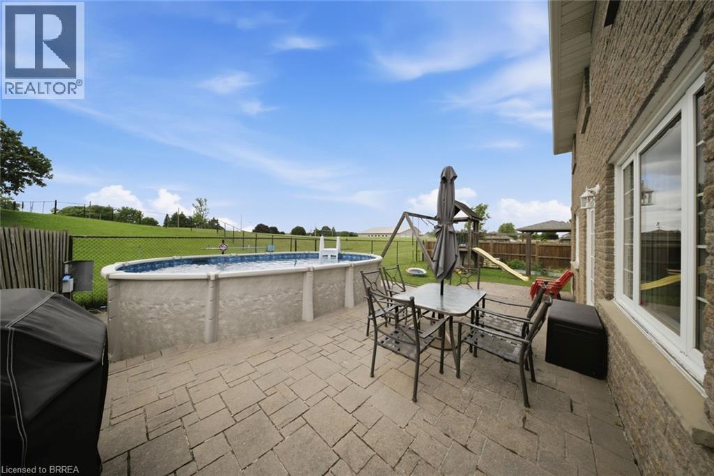 Expansive paved patio with an above-ground pool - 61 Sunnyside Drive, St. George, ON
