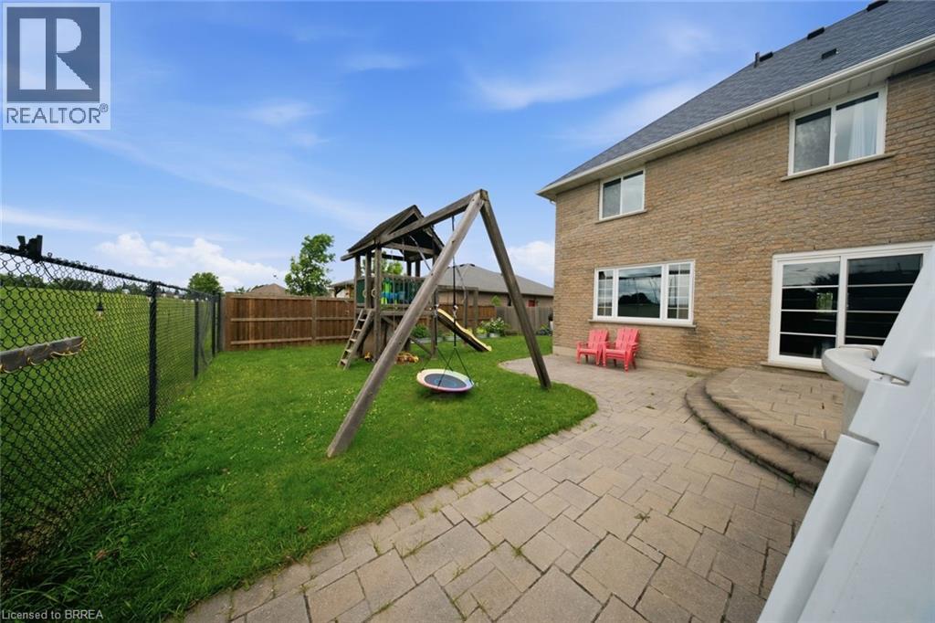 Rear exterior featuring a brick facade, multiple windows, and a sliding glass door - 61 Sunnyside Drive, St. George, ON