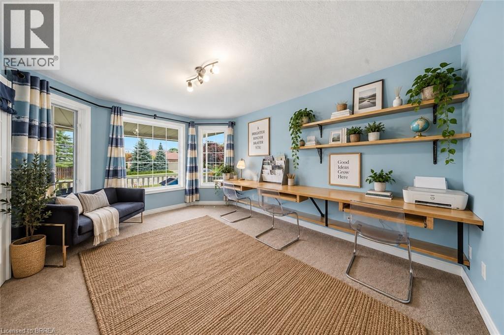 Bay windows, light blue walls, built-in wooden desk, open wooden shelving, and carpeted flooring - 61 Sunnyside Drive, St. George, ON