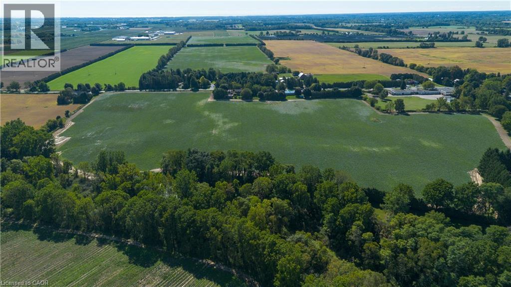 Expansive agricultural land featuring cultivated fields, natural tree lines, and distant rural structures - 264 Old Highway 24, Waterford, ON