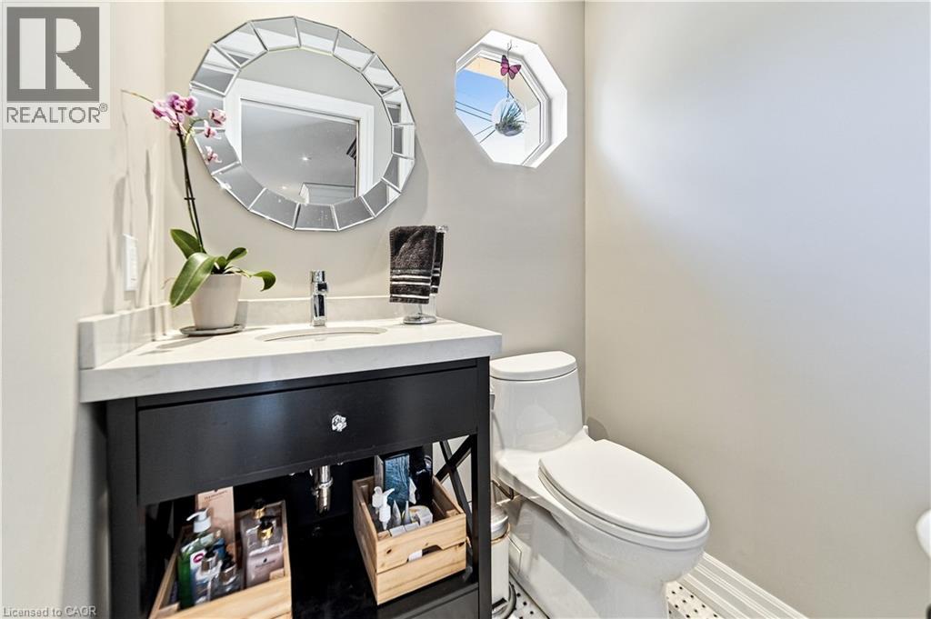 Vanity with a marble countertop, undermount sink, and a single-handle faucet. One piece toto toilet and octagon window. Mosaic floor tile. - 58 Uplands Avenue, Hamilton, ON