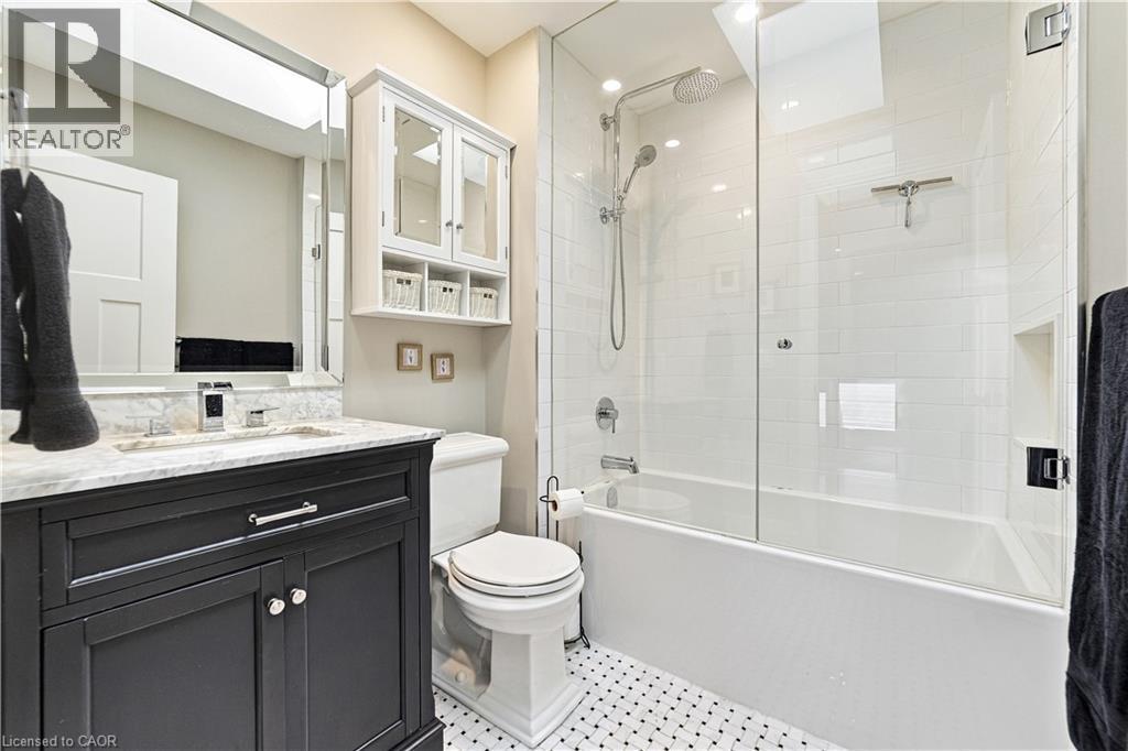 Dark vanity with marble top, mosaic tiling, glass tub surround and white ceramic tiling. Toto toilet - 58 Uplands Avenue, Hamilton, ON