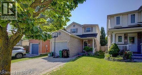 Brick and siding exterior featuring a covered front porch, an attached garage, a paved driveway, and a manicured lawn - 223 Melran Drive, Cambridge, ON 