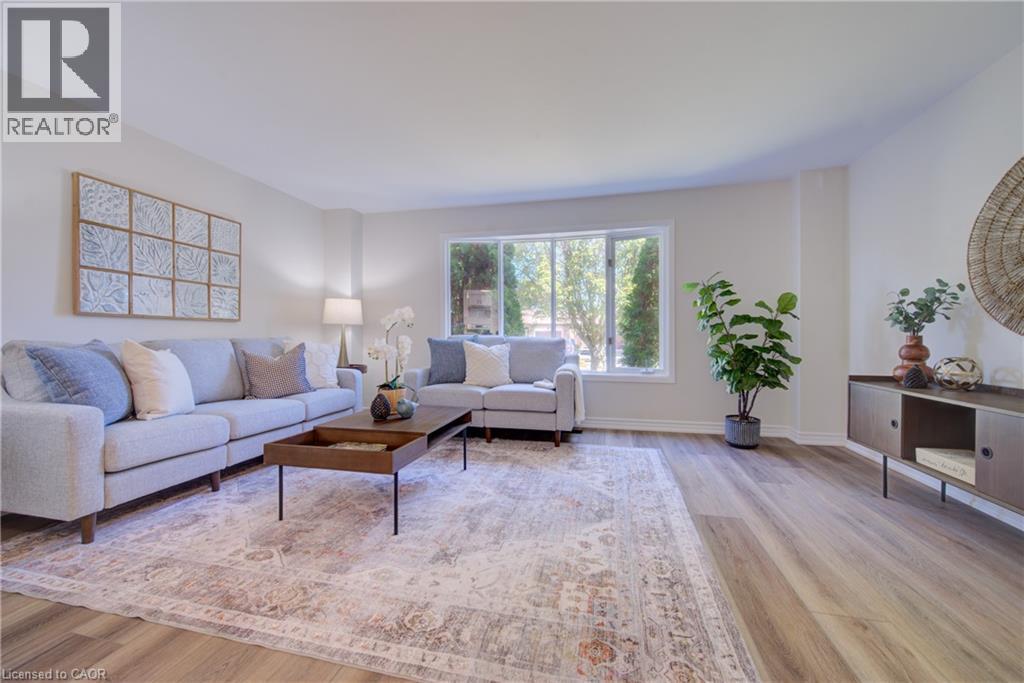 Bright living area featuring wood-finish flooring, white walls, and a large window - 39 Connelly Drive, Kitchener, ON