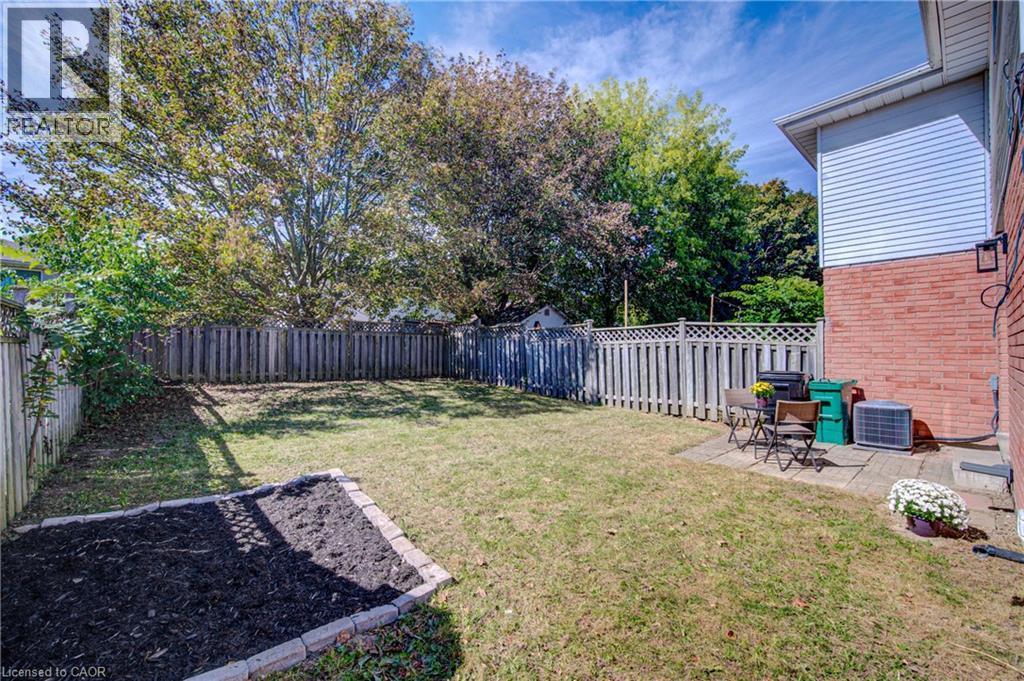 Expansive backyard with a manicured lawn, full privacy fencing, and a brick-edged garden bed - 39 Connelly Drive, Kitchener, ON