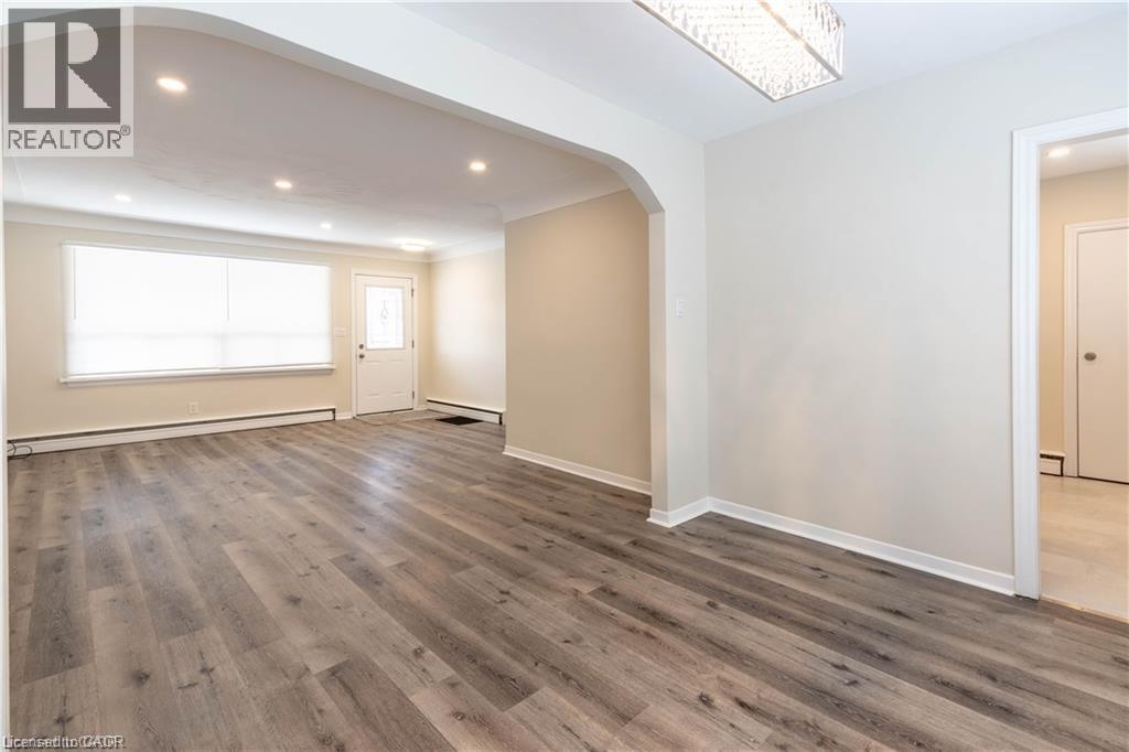 Wood-finish flooring, recessed ceiling lights, an arched doorway, and a decorative rectangular light fixture - 499 East 16Th Street, Hamilton, ON
