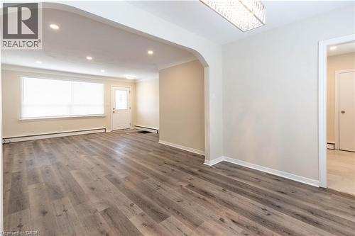 Wood-finish flooring, recessed ceiling lights, an arched doorway, and a decorative rectangular light fixture - 499 East 16Th Street, Hamilton, ON 