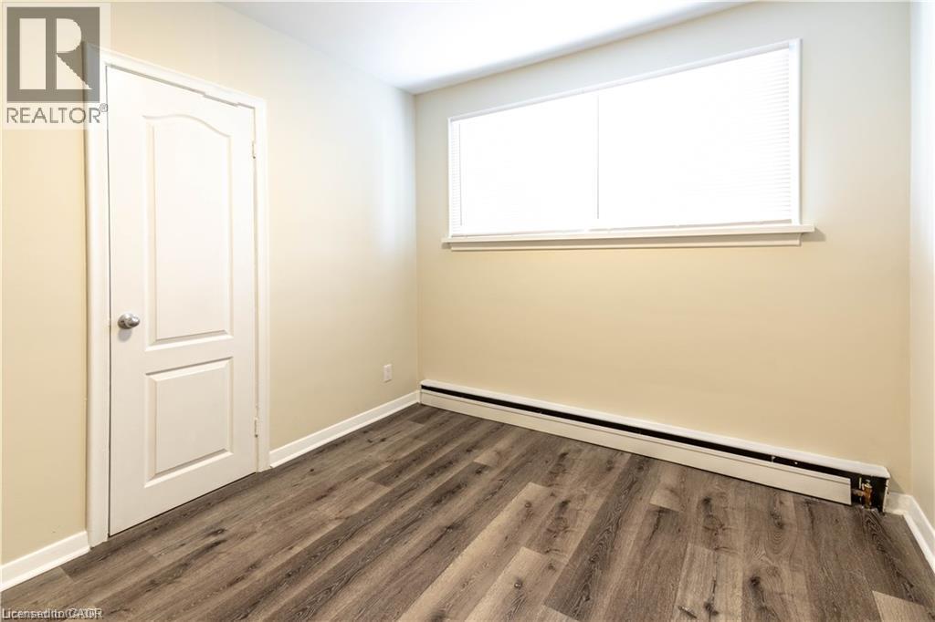 Wood-finish flooring, neutral wall tones, white trim, and a window with horizontal blinds - 499 East 16Th Street, Hamilton, ON