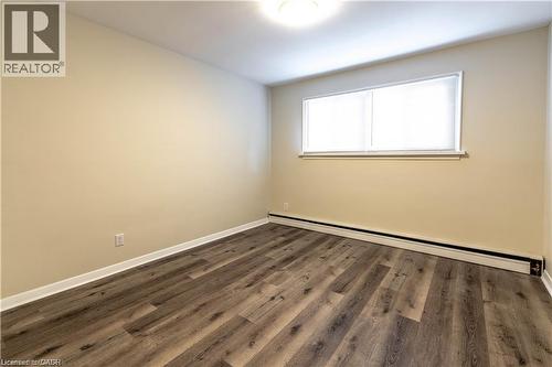 Wood-finish flooring, white trim, rectangular window with blinds, ceiling-mounted light fixture, light-toned walls - 499 East 16Th Street, Hamilton, ON 