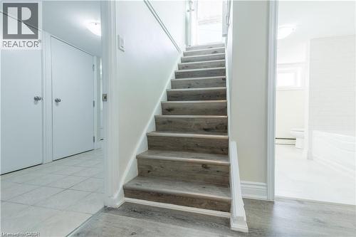 Wood-finish staircase, white interior doors, and light tile flooring - 499 East 16Th Street, Hamilton, ON 
