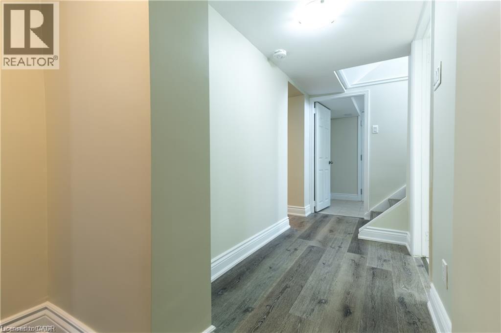 Hallway featuring wood-finish flooring, white trim, and light-toned walls - 499 East 16Th Street, Hamilton, ON