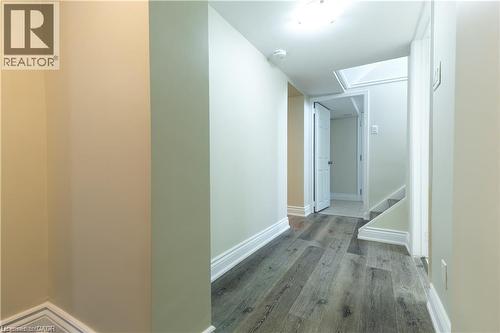 Hallway featuring wood-finish flooring, white trim, and light-toned walls - 499 East 16Th Street, Hamilton, ON 