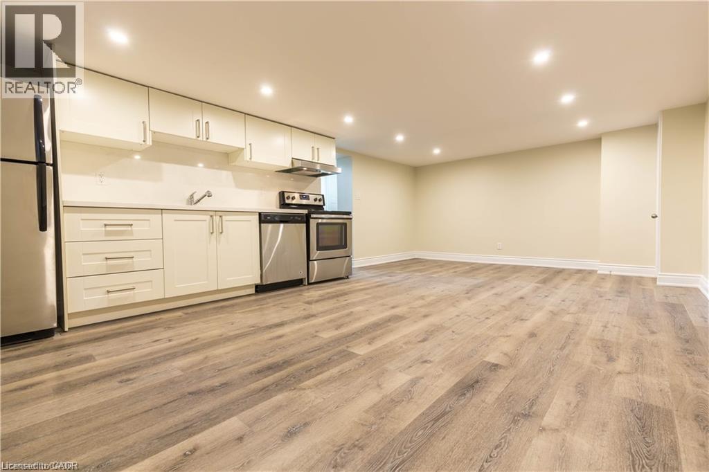 Laminate wood-finish flooring, recessed lighting, white cabinetry, stainless steel appliances, and a solid surface countertop - 499 East 16Th Street, Hamilton, ON