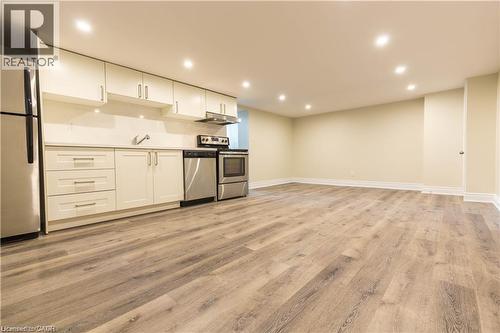 Laminate wood-finish flooring, recessed lighting, white cabinetry, stainless steel appliances, and a solid surface countertop - 499 East 16Th Street, Hamilton, ON 