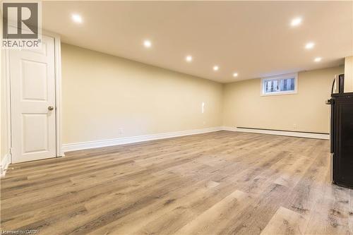 Spacious room featuring light wood-finish flooring, recessed ceiling lighting, a white panel door, and a horizontal window - 499 East 16Th Street, Hamilton, ON 