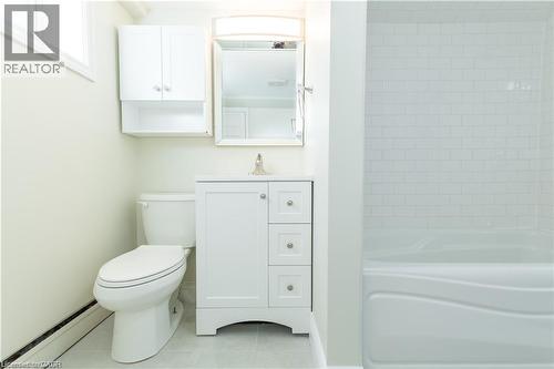 Bathroom featuring white subway tile shower surround, single vanity with integrated sink, white cabinetry with silver hardware, and a wall-mounted medicine cabinet - 499 East 16Th Street, Hamilton, ON 