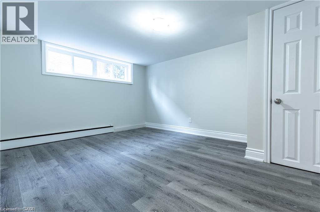 Wood-finish flooring, white trim, recessed window, white paneled door, and overhead lighting - 499 East 16Th Street, Hamilton, ON