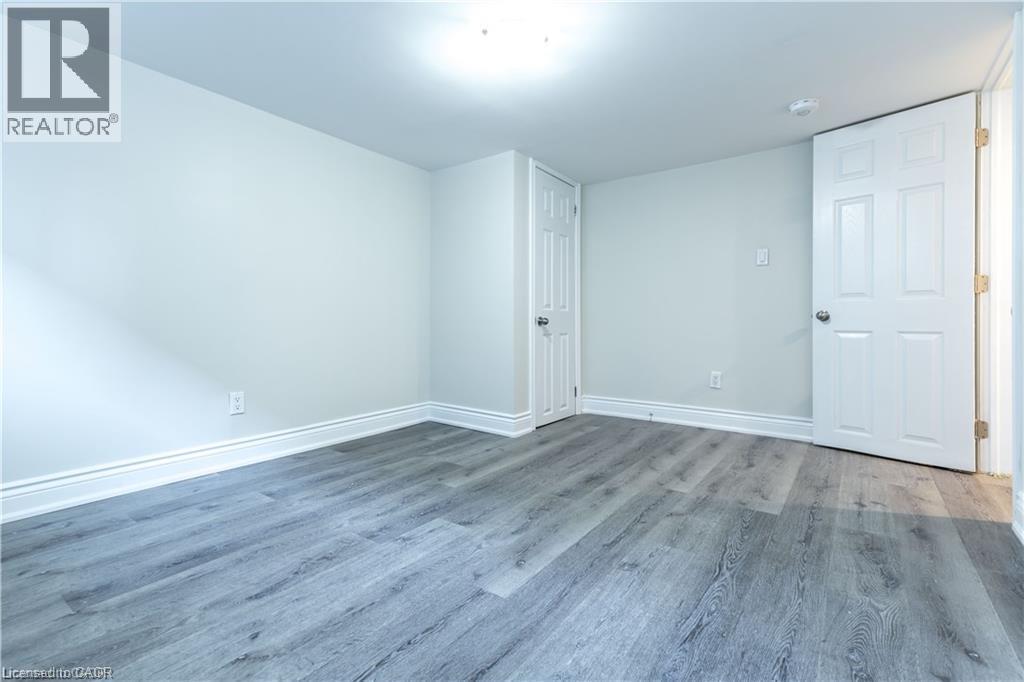 Wood-finish flooring, white trim, and a white ceiling with an overhead light fixture - 499 East 16Th Street, Hamilton, ON