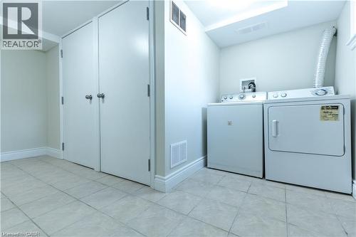 Washer and dryer appliances with tile flooring, white baseboards, and built-in storage - 499 East 16Th Street, Hamilton, ON 