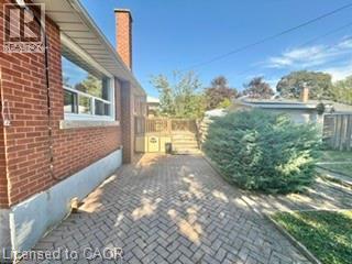 Brick exterior with a prominent chimney, complemented by a herringbone pattern paver driveway - 499 East 16Th Street, Hamilton, ON