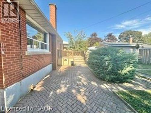 Brick exterior with a prominent chimney, complemented by a herringbone pattern paver driveway - 499 East 16Th Street, Hamilton, ON 