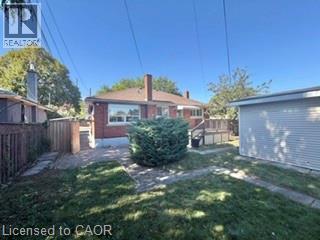 Brick exterior with a gabled roof, rear wood deck, and detached garage - 499 East 16Th Street, Hamilton, ON