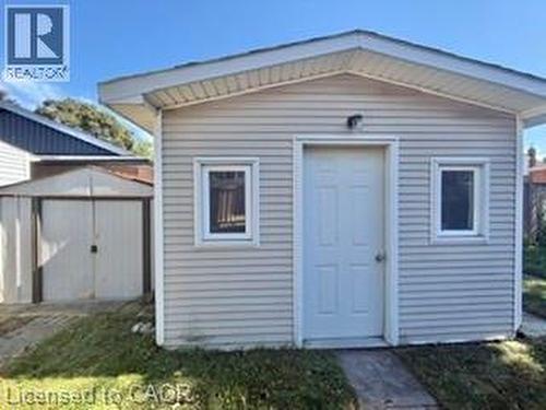 Shed structure featuring horizontal siding, a paneled entry door, and a single-pane window - 499 East 16Th Street, Hamilton, ON 