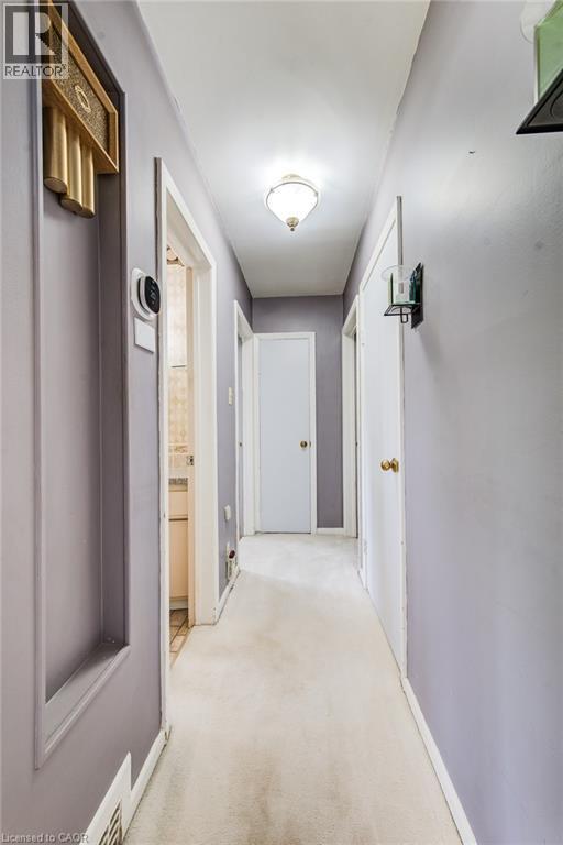 Hallway with carpet flooring, recessed wall niche, and an overhead flush-mount light fixture - 192 Warren Road, Kitchener, ON
