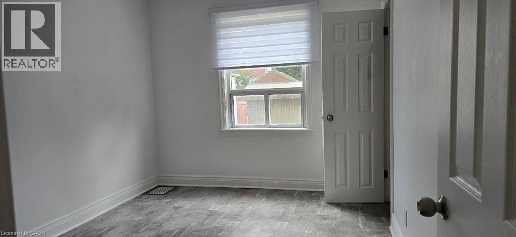 Wood-finish flooring, white paneled door, and a single window with blinds - 284 Brucedale Avenue E, Hamilton, ON