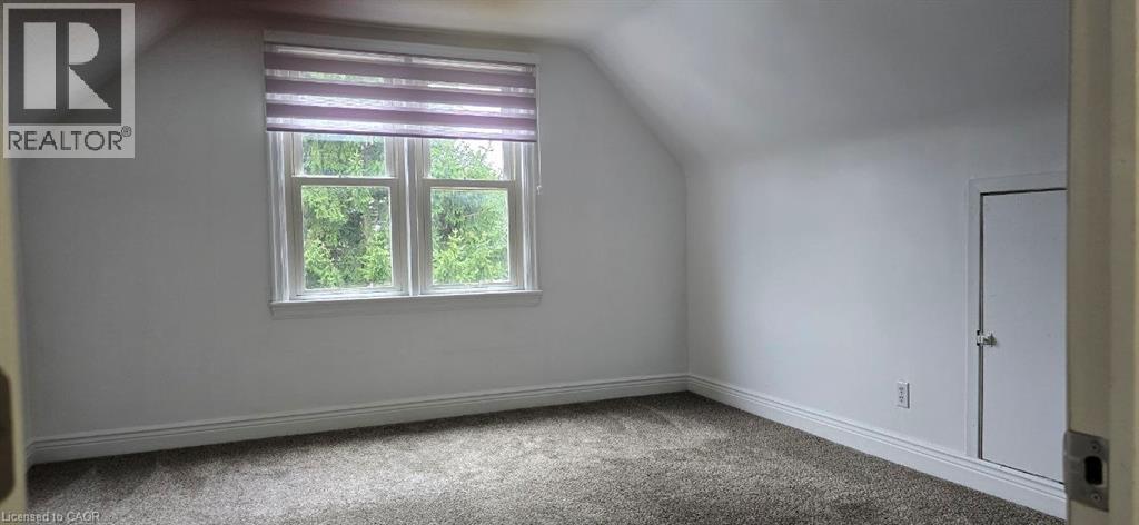 Carpeted room with a double-pane window, white trim, and a white door - 284 Brucedale Avenue E, Hamilton, ON