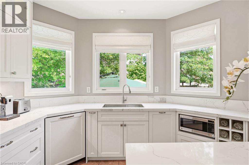 Bright, light-filled kitchen featuring white cabinetry with shaker-style doors, quartz countertops, and a centered undermount sink with polished nickel faucet - 536 Cusick Circle, Milton, ON