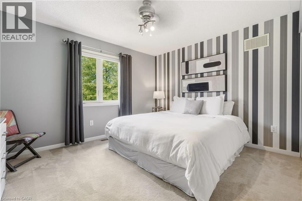 Primary bedroom featuring a striped accent wall with integrated shelving, carpeted flooring, a sliding glass door with thermal-insulated framing, and recessed ceiling lighting - 536 Cusick Circle, Milton, ON