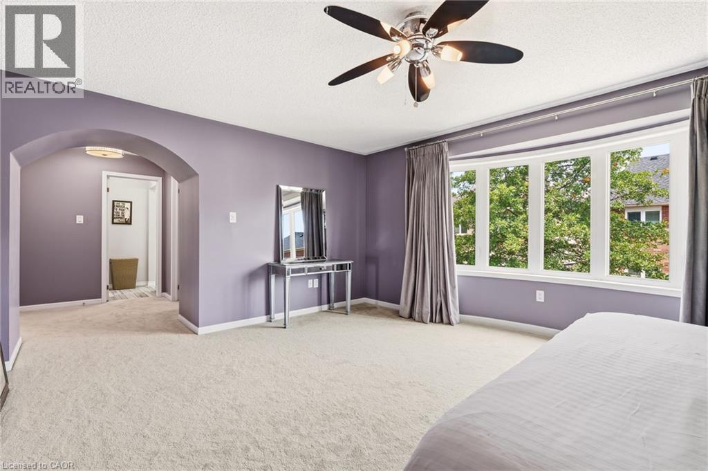 Spacious primary bedroom suite with soft purple walls, ceiling fan with brushed nickel finish, and abundant natural light from multi-pane windows - 536 Cusick Circle, Milton, ON