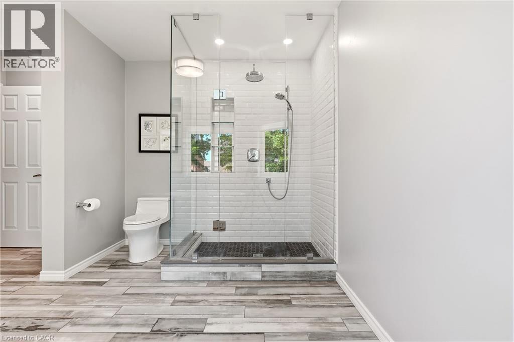 Spa-inspired primary bathroom featuring a frameless glass walk-in shower enclosure with subway tile surround, dual showerheads, a separate toilet compartment, wood-finish plank flooring, and recessed - 536 Cusick Circle, Milton, ON