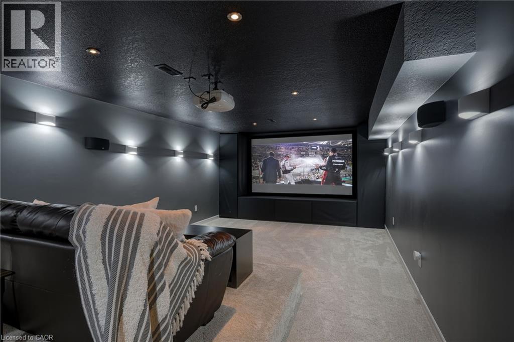 Dedicated media room featuring a large projection screen, recessed lighting, wall-mounted sconces, and built-in speakers - 536 Cusick Circle, Milton, ON