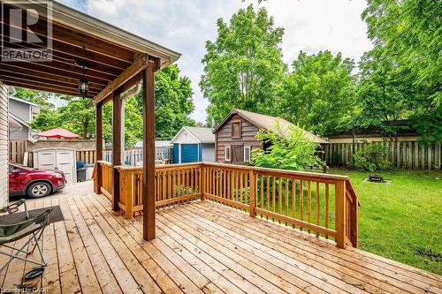 Expansive wooden deck with a covered area and railing, featuring a large grassy yard and a detached shed - 275 Main Street, Cambridge, ON 