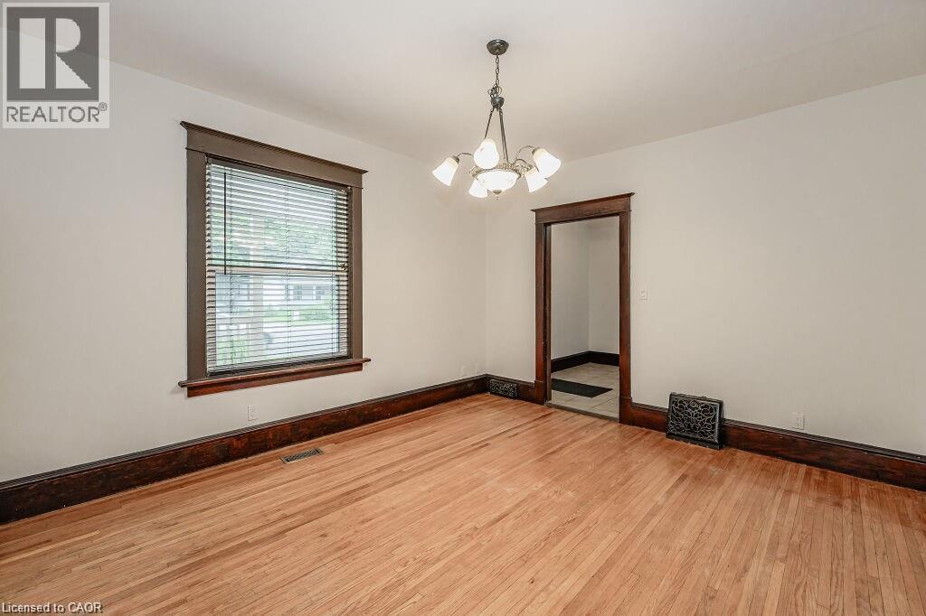 Hardwood flooring, white painted walls, dark wood trim, classic chandelier, and a doorway with dark wood framing - 275 Main Street, Cambridge, ON