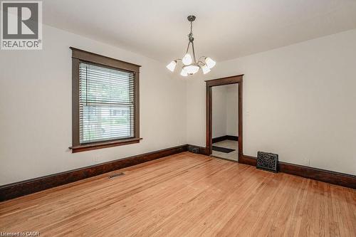 Hardwood flooring, white painted walls, dark wood trim, classic chandelier, and a doorway with dark wood framing - 275 Main Street, Cambridge, ON 